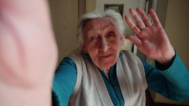 Cinematic shot of happy modern grandmother is using smartphone for navigate in internet, send messages and make calls at home. Concept of  technology, modern generation,family entertainment,connection