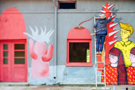 Female Graffiti Artist Writing On Wall