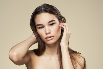Fototapeta premium Pretty woman naked shoulders long hair body care beige background