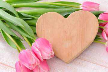 Beautiful flowers and wooden heart on light background