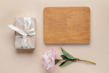 Beautiful flower, gift and wooden board on color background