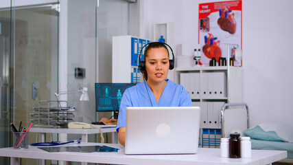 Assistant offering medical services using headphone answering calls, making appointments. hospital...