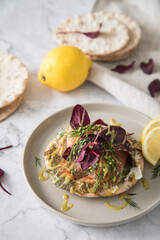 Gravlax Graved Lachs auf Knäckebrot mit Rote Beete Blätter Salat, Dill, Fischkäse, Skandinavische Senf Soße, Zitrone auf hell Marmor Hintergrund mit Leinen Tuch als Vorspeise oder Snack
