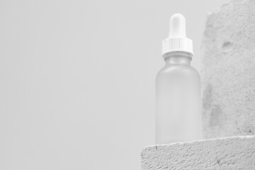 Glass jar of skincare serum on concrete block