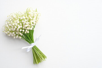 Bouquet of flowers lily of the valley on white background. Flat lay, top view with copy space. Greeting card mockup for Mother's Day, Woman's Day