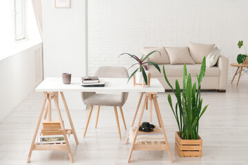 Modern work place in living room or studio, natural light, home plants