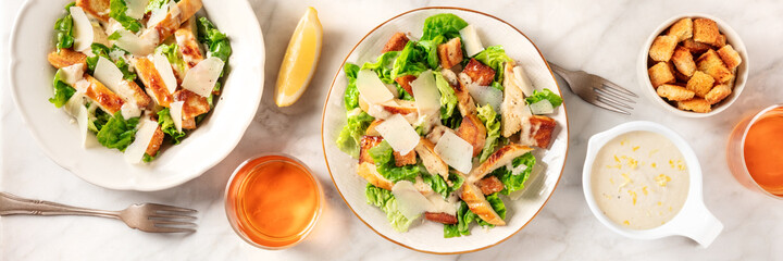 Caesar salad panorama, a flat lay with sauce, croutons, and wine