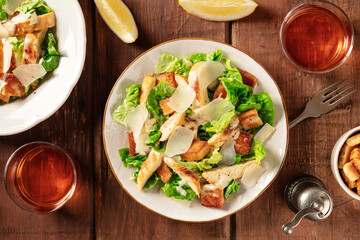 Caesar salad, shot from above with wine on a dark rustic wooden background