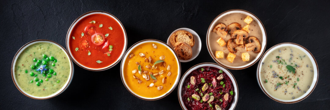 Vegan soup panoramic banner. Various vegetable soups, shot from above, a flat lay on a black background