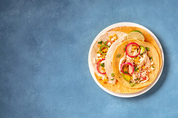 Mexican tacos with chicken, avocado, and sweet corn, overhead shot on a blue background with a place for text