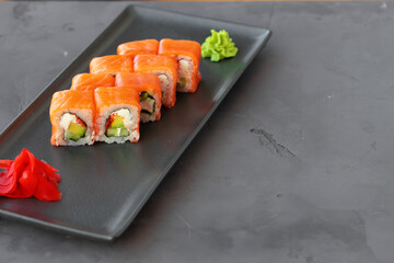 Philadelphia sushi roll served on black ceramic plate