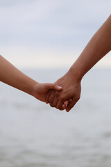Young people holding hands on calm sea background.