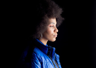 pretty mixed afro woman, smiling, with serious urban clothes, sad look, on dark background