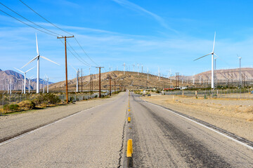 Long straight road with windmills background at California, USA.