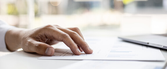 Close-up of a businessman's hand on a company finance document, a businessman examining the financial data from a company finance chart. Financial concept.
