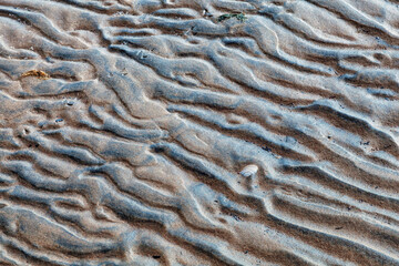 Wavy sand texture created by ocean waves. Beautiful patterns in the sand formed by wind on the beach sand texture