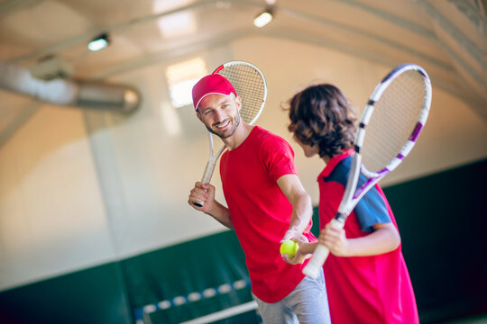 Young bearded man in a red cap talking to a boy before the game