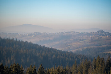 Fototapeta na wymiar Babia Góra Mount seen from Bukowina Tatrzańska, Poland. Smog is covering the hills and filling cold winter air. Selective focus on the forest, blurred background.
