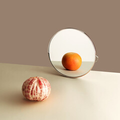 Mirror reflection of grapefruit peeled one opposite whole fruit. Beige color domination in the background.