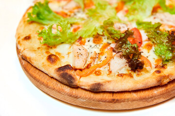 Pizza with cheese, bacon, tomatoes and lettuce on wooden board. Close-up, selective focus.
