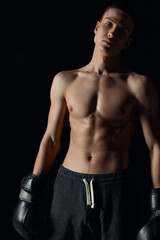 Fototapeta na wymiar bodybuilders boxing gloves on black background and gray pants athlete model