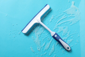 Window сleaning squeegee on blue background with foam