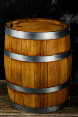 Fototapeta premium A beautiful wooden barrel and a worn oak wood table set against a dark wall pattern for the design