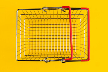Top view of a supermarket shopping cart on a trendy yellow background. The concept of sales