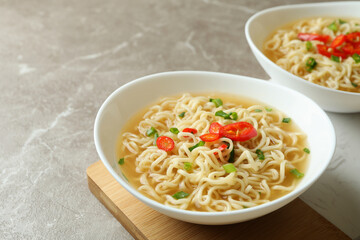 Concept of tasty eating with bowls of noodles on gray background