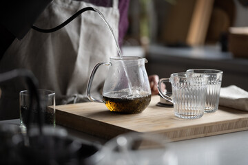 Woman is making hot tea in the kitchen.