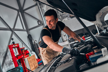 Fototapeta na wymiar Mechanic in car service repairs in the engine compartment.
