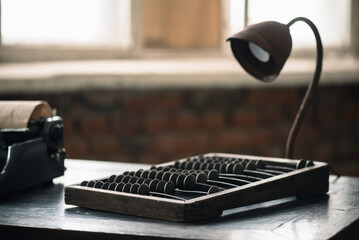 Retro typewriter, old abacus and lamp on the antique desk table background. Writer or accountant table.