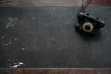 Old retro rotary phone on the black office antique desk table flat lay background.