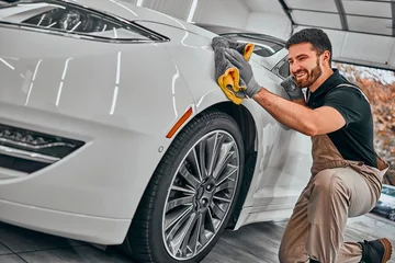 Foto op Canvas Man cleaning car and drying vehicle with microfiber cloth. Hand wipe down paint surface of shiny white car after polishing and ceramic coating. © HBS