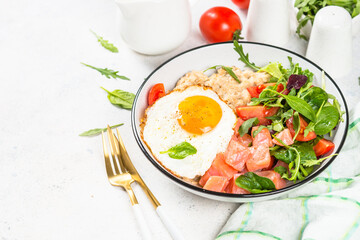 Savory breakfast at white. Oatmeal porrige with salted salmon, egg and fresh salad.