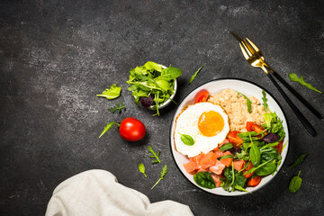 Savory breakfast. Oatmeal porrige with salted salmon, egg and fresh salad. Top view on black table.
