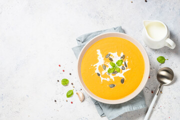 Pumpkin soup with cream. Top view image at white table.