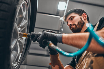 Professional car mechanic working with in auto repair service. Repair of wheels © HBS
