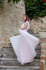 Beautiful woman with purple hair in a white wedding dress walks in the garden. Natural makeup