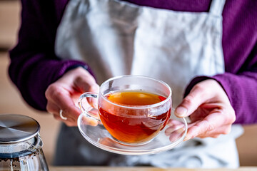 Woman holding cup of hot black tea.
