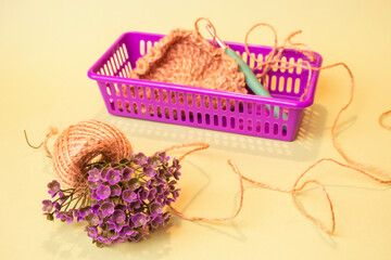 Fototapeta na wymiar Yarn in the basket. Plastic basket with jute yarn. Crochet a circle of jute rope. Jute twine. Circle crocheted from jute.