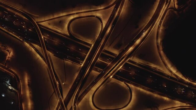 High altitude aerial top-down shot of a highway intersection traffic at night in winter