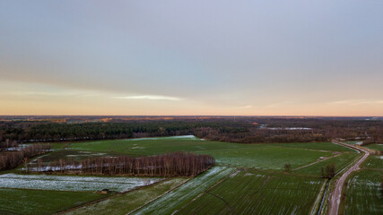 Fototapeta premium Aerial view of a beautiful and dramatic sunset over a forest lake reflected in the water, landscape drone shot. Blakheide, Beerse, Belgium. High quality photo