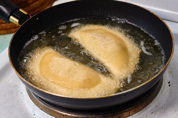Process with  fried in sunflower oilof homemade qutab or chebureki, calzone with minced meat and onion. Process of making food at the kitchen. Azerbaijani, Tatar, Caucasian, Greek cuisine. 