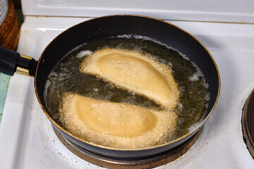 Process with  fried in sunflower oilof homemade qutab or chebureki, calzone with minced meat and onion. Process of making food at the kitchen. Azerbaijani, Tatar, Caucasian, Greek cuisine. 