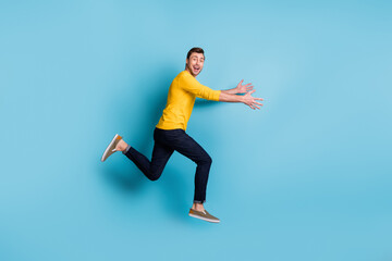 Fototapeta na wymiar Full length profile portrait of cheerful carefree guy run arms catching good mood isolated on blue color background
