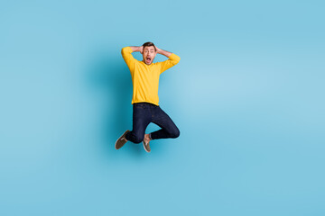 Full length photo of shocked young man arms on head open mouth staring isolated on blue color...