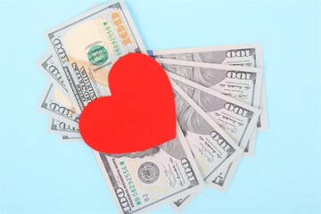 Red heart and Dollars banknotes on blue background. Business and love concept.