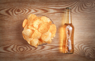 Potato chips and bottle beer on the wooden table.