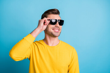 Portrait of attractive cool cheerful guy enjoying touching specs isolated over bright blue color...